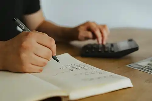 desk-with-hands-using-notebook-calculator