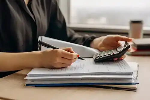 desk-with-hands-using-notebook-calculator